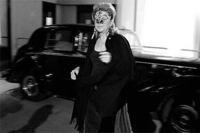 Una de las invitadas al baile, vestida de negro, con máscara y un abanico en la mano.