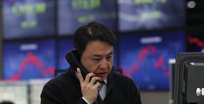 Un corredor de bolsa trabaja junto a monitores que ofrecen la informaci&oacute;n burs&aacute;til en Se&uacute;l (Corea). 