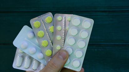 hand holds pills in packs on a green background
