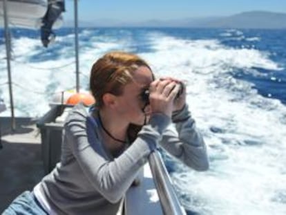 Una joven trata de avistar cetáceos con unos prismáticos en la expedición naútica organizada por Ambar y el CBE