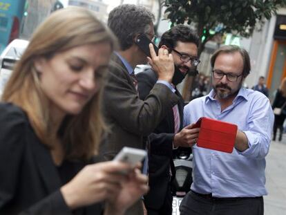 Varias personas usan sus dispositivos móviles en la Gran Vía de Madrid