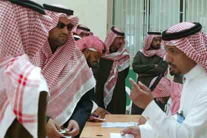 Varios electores escuchan instrucciones sobre cómo votar en un colegio electoral de Riad.