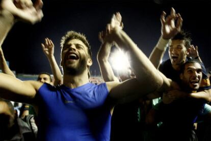 Piqué, en primer término, y Villa, a hombros de Pinto, celebran el título de Liga sobre el césped del Ciutat de València.