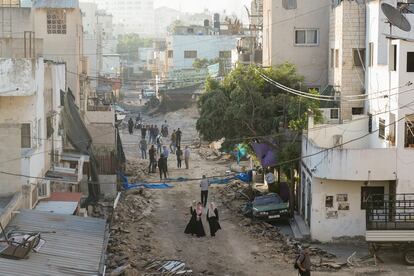 Palestinians walk on a damaged road following two days of Israeli military raid on the militant stronghold of the Jenin refugee camp in the West Bank,