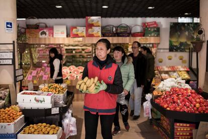 song Xiao Yan, de 62 años, diagnosticada con esquizofrenia compra frutas y verduras con sus colegas en un mercado fuera de la unidad abierta residencial de Vila Rosa para las personas con condiciones de salud mental en el distrito de Yinqing, Beijing, China.