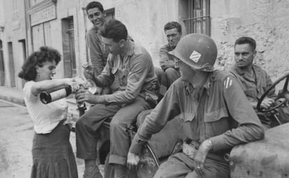 Una mujer sirve vino a soldados aliados durante la liberación de Francia.