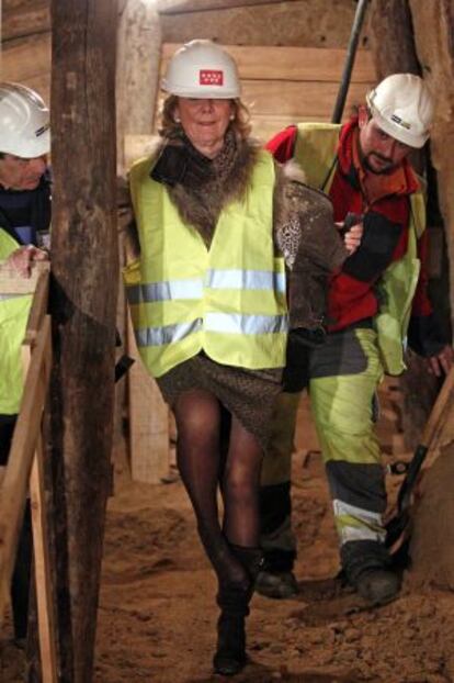 Esperanza Aguirre se quita la arena del calzado durante una visita a las obras del metro.