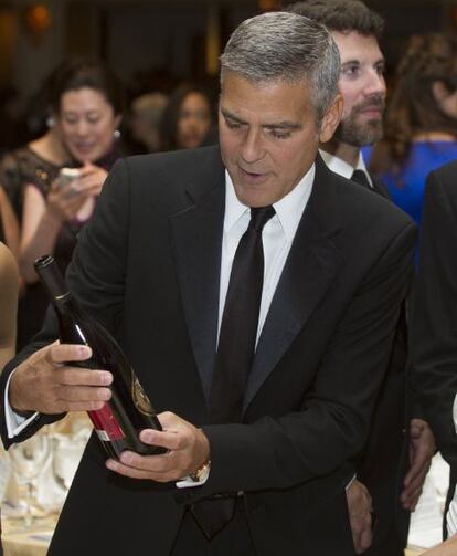 George Clooney contempla una botella de vino antes de sentarse a su mesa en la cena de corresponsales de la Casa Blanca.