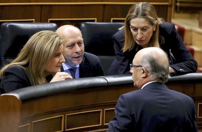 Fátima Báñez, ministra de de Empleo y Seguridad Social, José Ignacio Wert, responsable de la cartera de Educación, Cultura y Deporte, y Ana Pastor, de Fomento, atienden a Cristóbal Montoro, ministro de Hacienda y Administraciones públicas (de espaldas) en el hemiciclo.