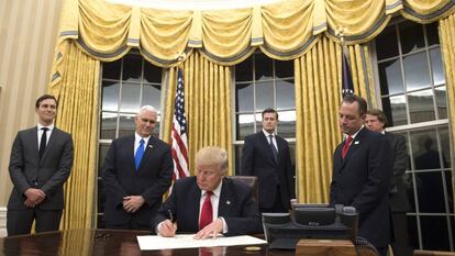 Donald Trump firma en el Despacho Oval frente a las nuevas cortinas doradas.