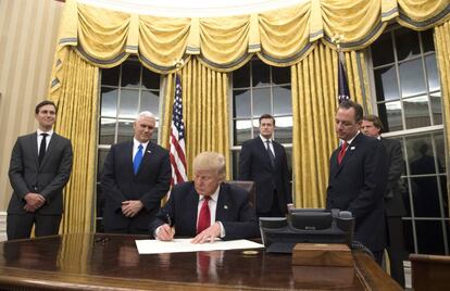 Donald Trump firma en el Despacho Oval frente a las nuevas cortinas doradas.