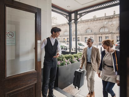 El conserje de un hotel da la bienvenida a dos huéspedes.