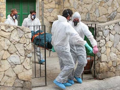 Trabajadores de una empresa funeraria de Palma trasladan un cadáver equipados con monos y mascarillas.