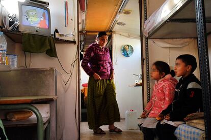 Dos de los niños ven la tele antes de ir al cole en el interior del autobús que ha sido su hogar desde 2008.