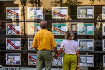 Una pareja observa el escaparate de una inmobiliaria en Madrid.