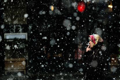 Una mujer fuma bajo en la nieve en la avenida Istiklal de Estambul.