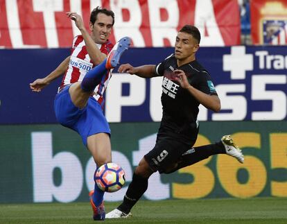 El defensa del Atlético de Madrid, Diego Godín, despeja la pelota ante el delantero argentino del Granada, Ezequiel Ponce