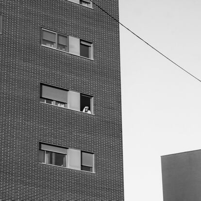 Un vecino mirando por la ventana, en el Ensanche Sur (Alcorcón).