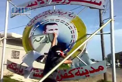 Un hombre rompe un cartel de El Asad en Kfar Laha.