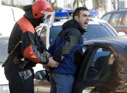 Un ertzaina detiene a uno de los jóvenes concentrados en Vitoria.