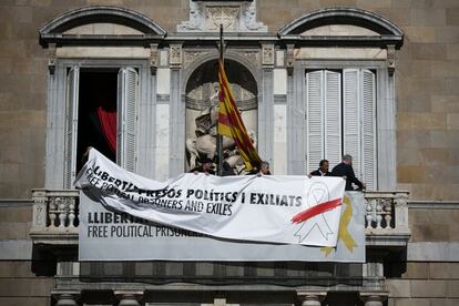 Trabajadores cambian la pancarta por otra sin el lazo amarillo en el Palau de la Generalitat.