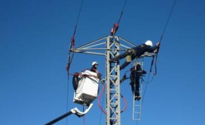 Unos operarios trabajan en un poste de electricidad.