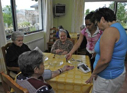 Una trabajadora del centro toma la tensión a una de las habitantes de la casa antes de servir la comida.