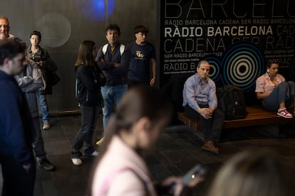 Varias personas se congregan a la entrada de Radio Barcelona para mantenerse informados durante el apagón.