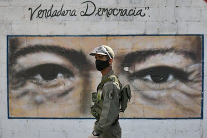 Un soldado custodia una escuela de Caracas en cuya pared tiene los ojos de Hugo Chávez, en las elecciones legislativas del 6 de diciembre pasado.