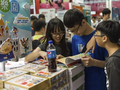 Varios j&oacute;venes ojean un libro en la 27&ordf; edici&oacute;n de la feria del libro de Hong Kong 