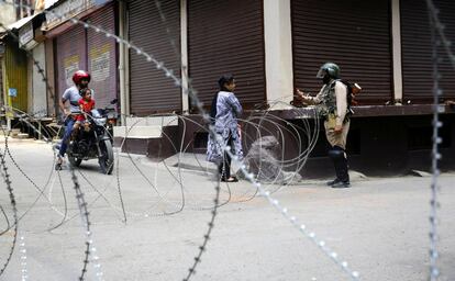 Un soldado paramilitar indio supervisa la documentación de una mujer cerca de una barricada policial durante las restricciones aplicadas en el centro de Srinagar (India) con el fin de frustrar las protestas surgidas tras la prohibición de la oración musulmana de los viernes en la histórica mezquita de Srinagar.