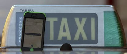 Un móvil con la aplicación de Uber junto a un taxi, esta semana en Madrid.