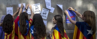 Varias estudiantes enganchan carteles en la pared de la Universidad de Barcelona