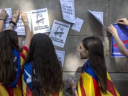 Varias estudiantes enganchan carteles en la pared de la Universidad de Barcelona