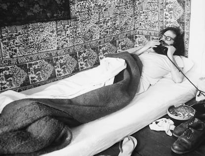 Allen Ginsberg acostado en su casa hablando por teléfono.