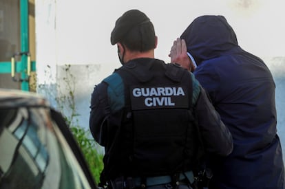 Uno de los detenidos en la operación es custodiado por un agente de la Guardia Civil.