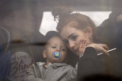 Una mujer sostiene a su bebé mientras abandonan Kiev en un autobús repleto de personas.