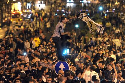 Un madridista ondea una bandera encaramado a un semáforo, en Cibeles