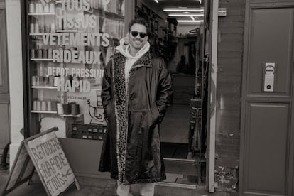 Matt Dillon, smiling in Paris while wearing a Giorgio Armani coat, a Champion sweatshirt, Levi's jeans and Persol sunglasses.