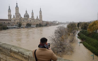 El presidente del Gobierno, Pedro Sánchez, viaja este martes a Navarra, La Rioja y Aragón para supervisar los daños causados por la crecida, acompañado por los respectivos presidentes autonómicos. En la imagen, un joven fotografía el río Ebro, desde el puente de Piedra, a su paso por Zaragoza, este martes.