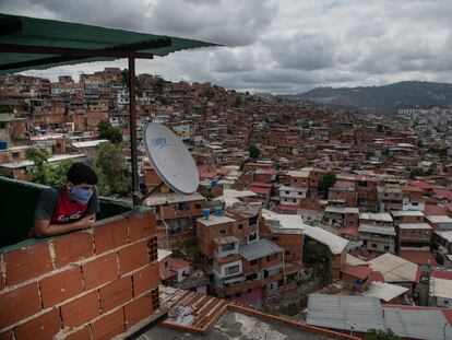 Una persona con cubrebocas observa las casas del barrio Petare, en Caracas, el 23 de marzo.