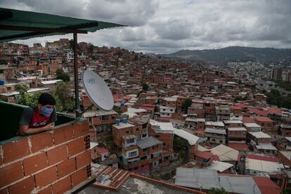 Una persona con cubrebocas observa las casas del barrio Petare, en Caracas, el 23 de marzo.