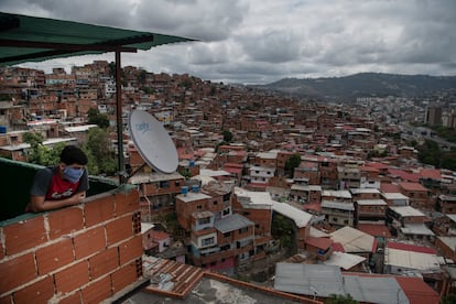 Una persona con cubrebocas observa las casas del barrio Petare, en Caracas, el 23 de marzo.