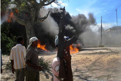 Miembros de la milicia islamista, delante de una casa en llamas en la localidad de Harar-Yale en el distrito de Wardhigley, al sur de Mogadiscio. El fuego empezó cuando se produjo un intercambio de disparos de mortero entre los milicianos y  fuerzas de la Unión Africana.