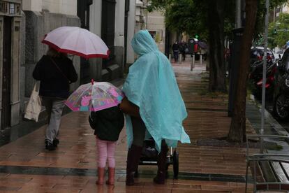 Una mujer y una niña pasean con paraguas en la capital en un día de lluvia.