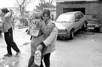 Una mujer ayuda a su hijo a salir de una zona inundada, ayer, en el barrio de la Estación de San Roque.