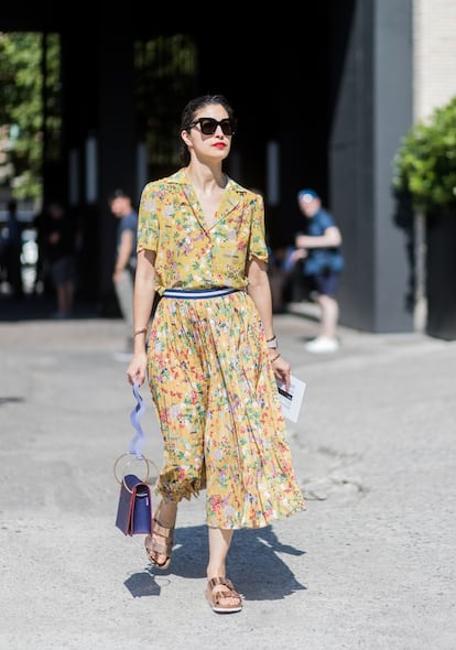 La editora de moda Caroline Issa a la salida de los desfiles de hombre de Milán, con un vestido de flores amarillo tipo pijama.