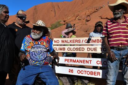 Con el cierre del sendero, se eliminará cualquier vestigio vinculado a esta actividad, como las cadenas y las señalizaciones que denominan el lugar como Ayers Rock, el nombre que se le dio en 1873 durante la colonización británica. En la imagen, aborígenes se colocan frente a la nueva señalización que prohíbe el paso en la base de Uluru.