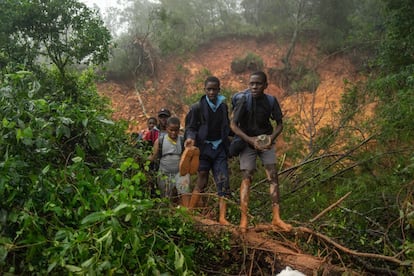 Estudiantes del colegio St. Charles Luanga, rescatados por miembros de las Fuerzas Armadas de Zimbabwe, pasan junto a un alud de lodo cubriendo una carretera principal en el cruce Skyline en Chimanimani, provincia de Manicaland, después de que el ciclón tropical Idai atravesara el sur de África provocando inundaciones y vientos feroces. El ciclón que azotó Mozambique y Zimbabwe mató al menos a 162 personas.