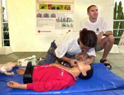 Dos voluntarios de Cruz Roja explican las maniobras de reanimación con la ayuda de un muñeco durante una Feria de los Primeros Auxilios. EFE/Archivo